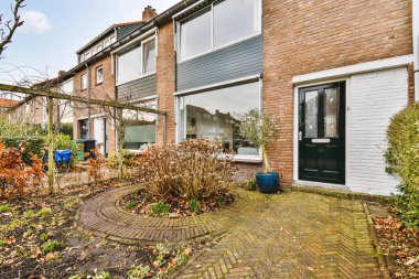 Ön bahçeden tuğla ev manzaralı, ahşap kapılı daire.