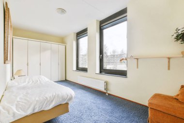 Beyaz dizaynlı halı zeminli geniş bir yatak odası.