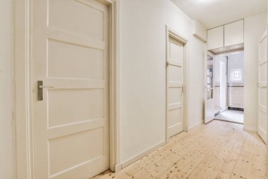 Geniş, düz bir koridor, birkaç kapısı var.