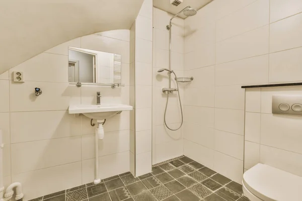 Łazienka z czarnymi płytkami na podłodze i zawiasową toaletą — Zdjęcie stockowe