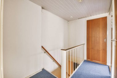 Geniş apartman koridorundaki ahşap merdiven.