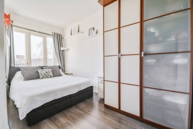 Ahşap gardıroplu aydınlık yatak odası.