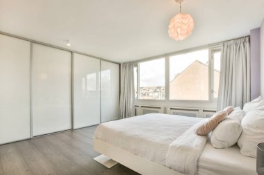 Ahşap gardıroplu aydınlık yatak odası.