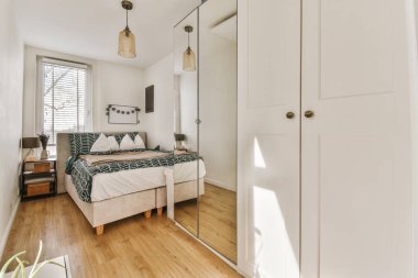 Ahşap gardıroplu aydınlık yatak odası.