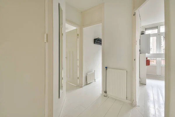 Light narrow hallway with many doors in white walls and glowing lamp over lumber floor