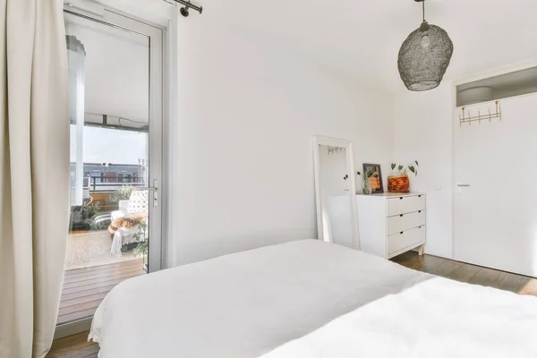 White bedroom with an entrance door to the balcony