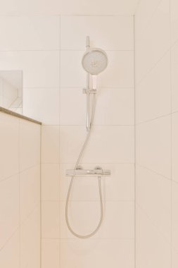 Duş muslukları cam bölmenin yanındaki fayanslı duvara bağlı ve evdeki tuvaletteki süs pervazı.