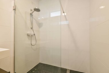 Duş muslukları cam bölmenin yanındaki fayanslı duvara bağlı ve evdeki tuvaletteki süs pervazı.