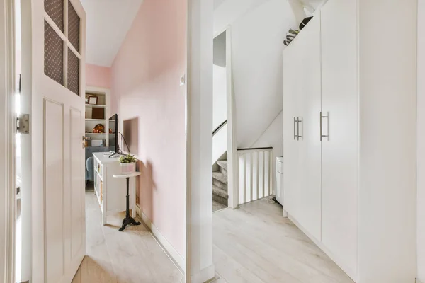 額装された写真や家の階段の上にスタイリッシュなランプの近くにある部屋の白いドア — ストック写真