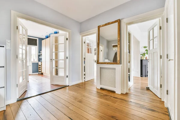 ミニマリストスタイルのアパートで鏡と寄木細工の床と白い壁とワードローブの空の狭い廊下のパースペクティブビュー — ストック写真