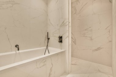 Beyaz fayanslı duvarları olan banyo ve aydınlıkta duş kabini