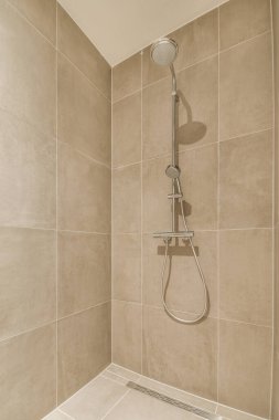 Duş muslukları cam bölmenin yanındaki fayanslı duvara bağlı ve evdeki tuvaletteki süs pervazı.