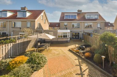 Oturma alanı ve ahşap çitlerin yanındaki küçük bahçesi olan düzgün asfaltlı bir avlu.