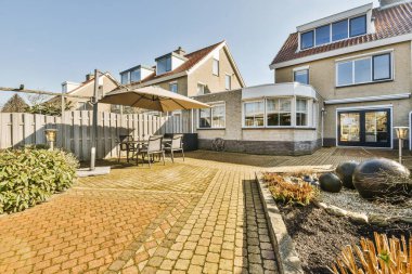 Oturma alanı ve ahşap çitlerin yanındaki küçük bahçesi olan düzgün asfaltlı bir avlu.