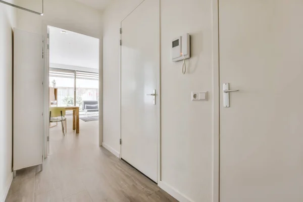 Light narrow hallway with many doors in white walls and glowing lamp over lumber floor