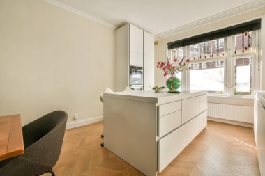 Modern apartmandaki dekorasyonlu ve televizyonlu, rahat koltuğun yanına yerleştirilmiş eski püskü ahşap masa.