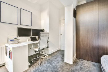 Boş tahtaya karşı bilgisayar monitörleri olan rahat sandalye ve çağdaş düz ev ofisinde ayna