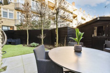 Neat paved patio with sitting area and small garden near wooden fence