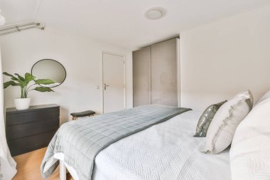 Çift büyük yatak, beyaz ve gri yastıklar, battaniyeler.