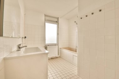 Evdeki çağdaş tuvaletteki aynanın altındaki duvarda musluk ve sıvı sabun asılı.