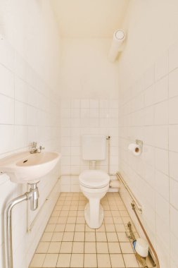 Modern sifon tuvaleti ve seramik lavabo aynanın yanındaki beyaz fayanslı duvarlara ve evdeki küçük tuvaletteki havluya monte edildi.