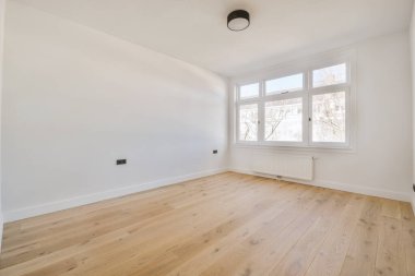 Evdeki boş ışık odasında, beyaz duvardaki plastik pencere ve radyatör.