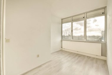 Evdeki boş ışık odasında, beyaz duvardaki plastik pencere ve radyatör.