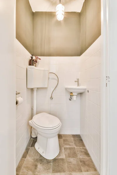 在靠近镜子的白色瓷砖墙上安装了现代冲水马桶和陶瓷水池 在家里的小卫生间里安装了毛巾 — 图库照片