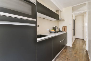 İyi organize edilmiş küçük bir ev mutfağı pencerenin altında lavabo, sobalı hafif mobilyalar ve kentsel apartmanda buzdolabı var.