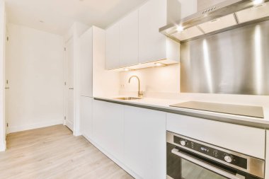 Koridoru ve ahşap parke zemini olan boş beyaz mutfağın içi.