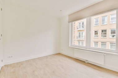 Evdeki boş ışık odasında, beyaz duvardaki plastik pencere ve radyatör.