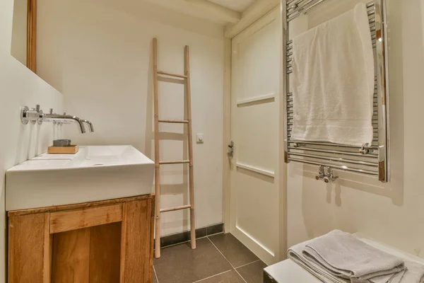 现代卫生间门边和烘干架上附有水槽和镜子的橱柜 — 图库照片
