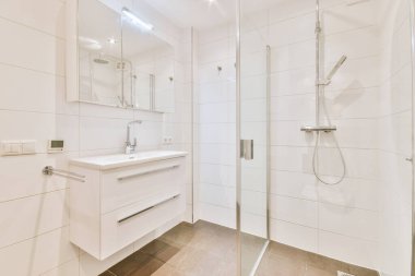 Duş dolabı, ayna, lavabo beyaz dolapta.