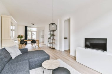 Modern apartmandaki dekorasyonlu ve televizyonlu, rahat koltuğun yanına yerleştirilmiş eski püskü ahşap masa.