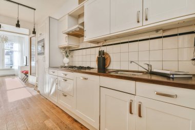 Koridoru ve ahşap parke zemini olan boş beyaz mutfağın içi.