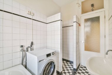 Lavabo ve aynalı dolap kapının yanındaki fayanslı duvara ve modern tuvaletteki kurutma tezgahına bağlı.