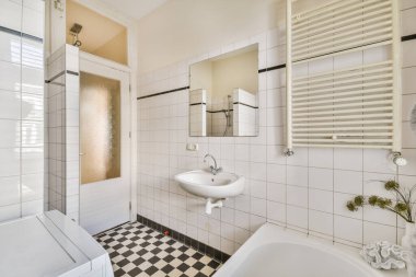 Lavabo ve aynalı dolap kapının yanındaki fayanslı duvara ve modern tuvaletteki kurutma tezgahına bağlı.