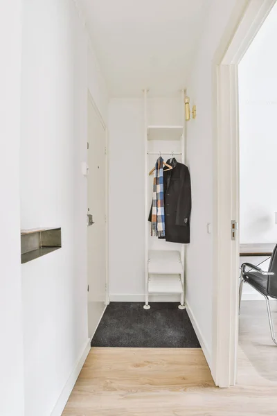 Light narrow hallway with many doors in white walls