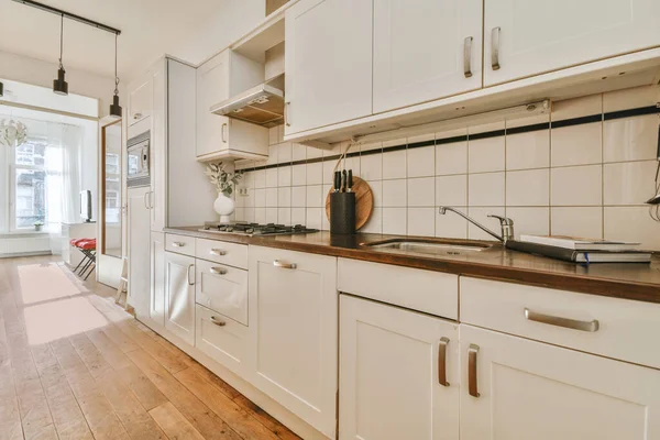 Koridoru ve ahşap parke zemini olan boş beyaz mutfağın içi.