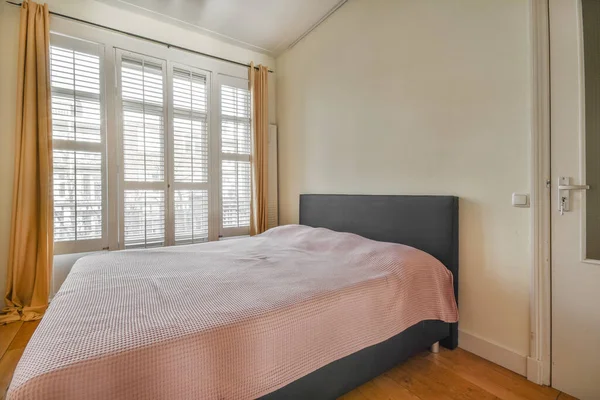 居心地の良い光の寝室でカーテン付きのバルコニードアの近くに位置する快適なベッド — ストック写真