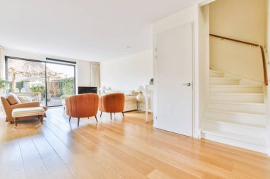 Beyaz ahşap merdivenlerin yanındaki beyaz kapı üst kata çıkıyor.