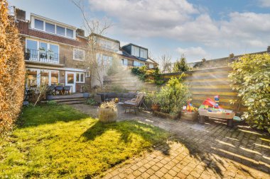 Oturma alanı ve ahşap çitlerin yanındaki küçük bahçesi olan düzgün asfaltlı bir avlu.