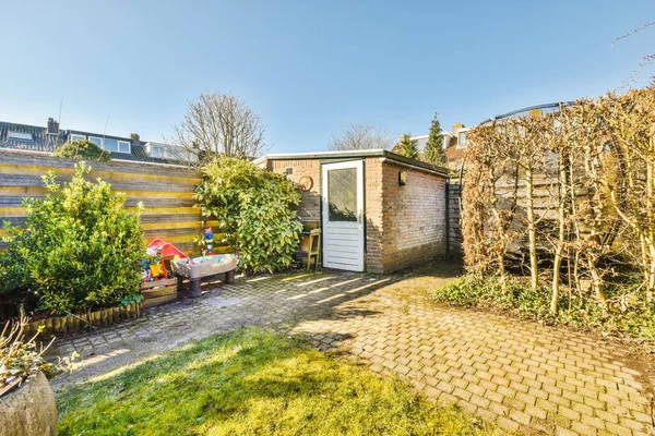 Oturma alanı ve ahşap çitlerin yanındaki küçük bahçesi olan düzgün asfaltlı bir avlu.