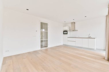 Pencereleri ve ahşap parke zemini olan boş beyaz mutfağın içi.