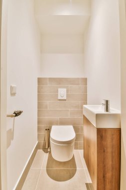 Modern sifon tuvaleti ve seramik lavabo aynanın yanındaki beyaz fayanslı duvarlara ve evdeki küçük tuvaletteki havluya monte edildi.