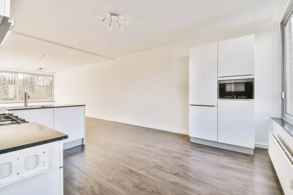 Contemporary counters and stools located under stylish exhaust hood in spacious light kitchen at home