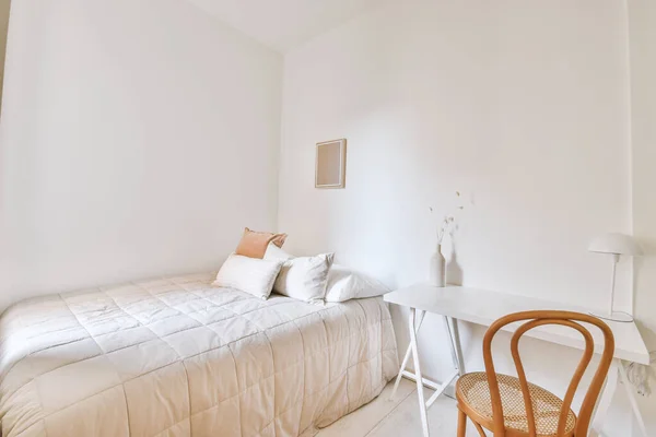 White bedroom with a work place with white wooden table and brown chair