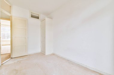 Modern dolap ve klasik sandık, beyaz duvarları ve ahşap zemini olan geniş bir odada, kapıların ve hasır sepetin yanına yerleştirildi.