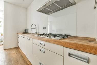 Minimalist tarzı beyaz mobilyalı, lavabolu ve sobalı bir ev mutfağı.