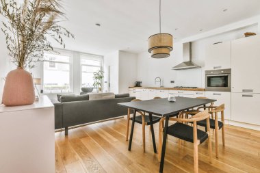 Modern apartmandaki dekorasyonlu ve televizyonlu, rahat koltuğun yanına yerleştirilmiş eski püskü ahşap masa.